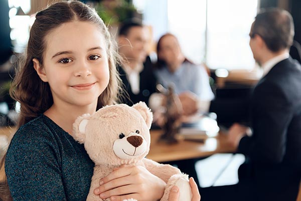 little girl smiling with teddy bear during divorce therapy