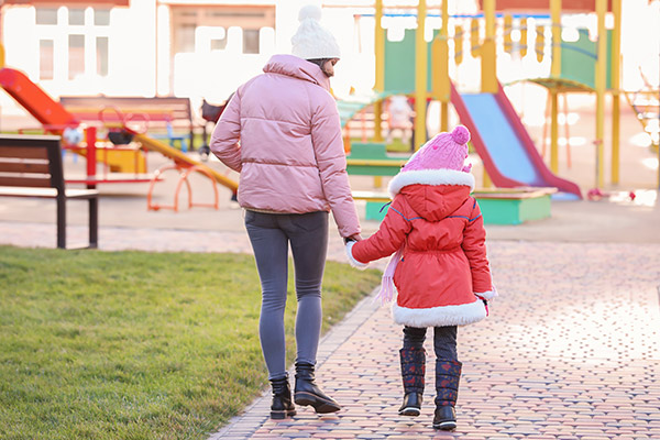 mother walking with daughter in neighborhood playground